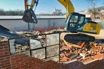 yellow and black excavator on brown brick wall during daytime